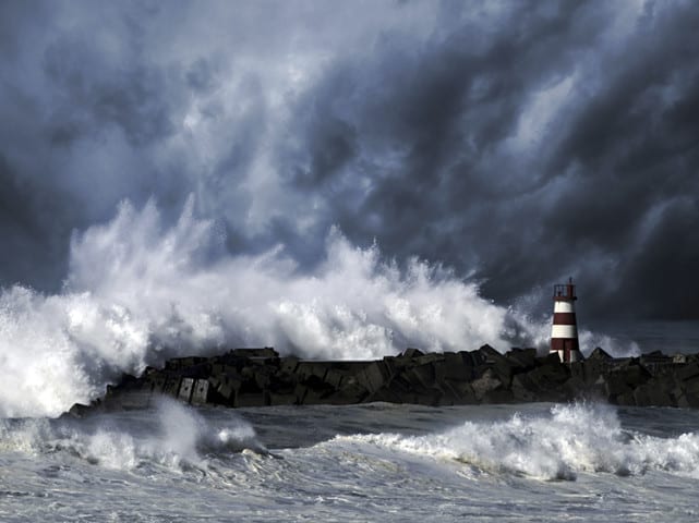 Storm waves over beacon of the harbor of Povoa do Varzim, Portugal - enhanced sky