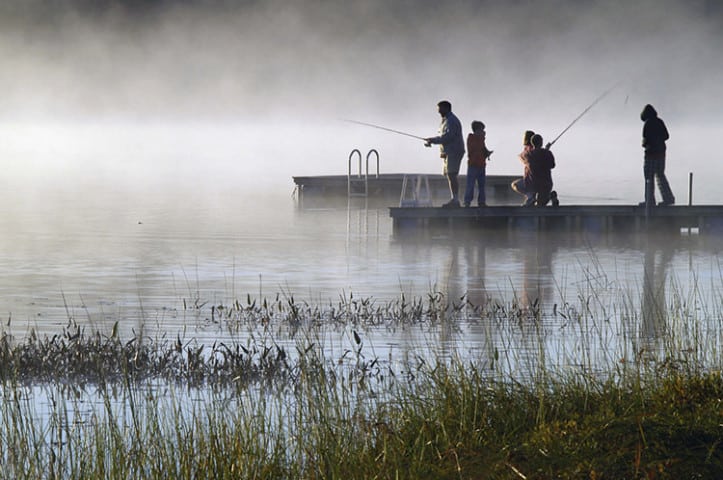 Early morning fishing in autumn on a lake as the mist rises from the water.